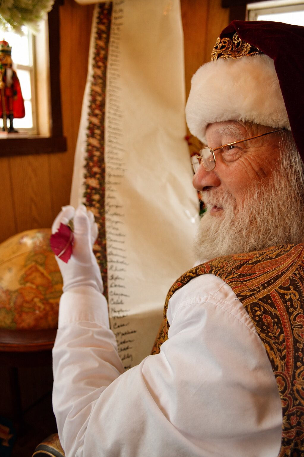 Santa holding his feather quill beside the long Christmas list